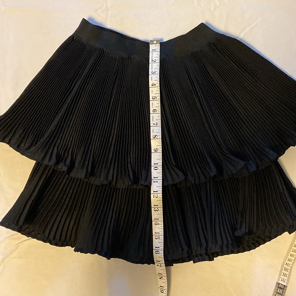 Black multi pleat mini skirt with 2 layers. No brand or size. W 24”, L 17” Nylon